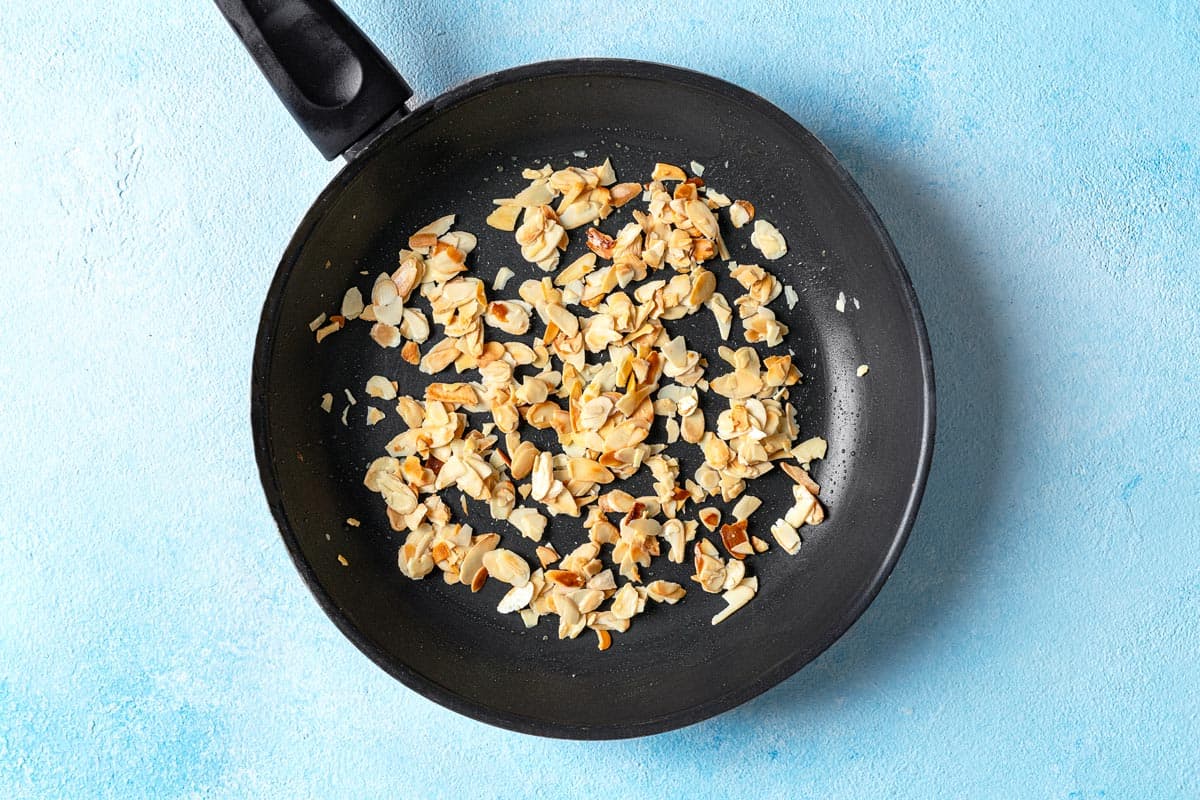 sliced almonds being toasted in a skillet.