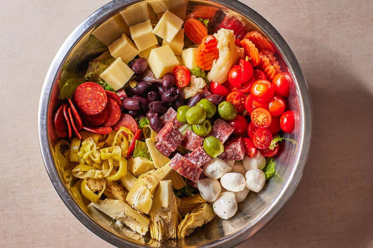 ingredients for the antipasto salad in a large bowl before being mixed together.