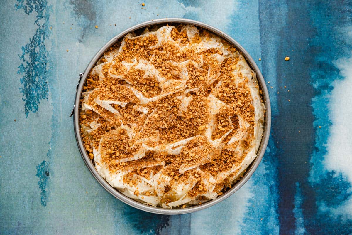 an unbaked baklava pumpkin pie topped with chopped walnut crumble.