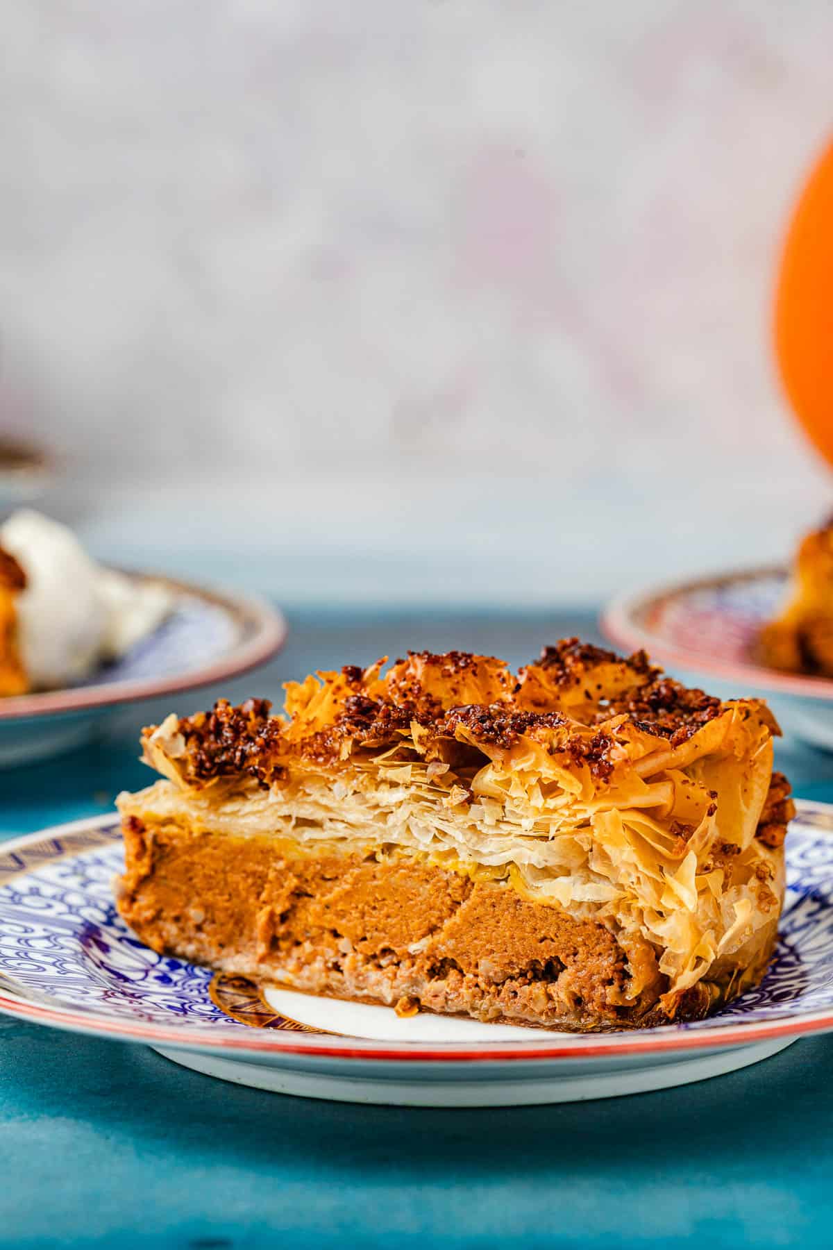 a close up of a slice of baklava pumpkin pie on a plate.