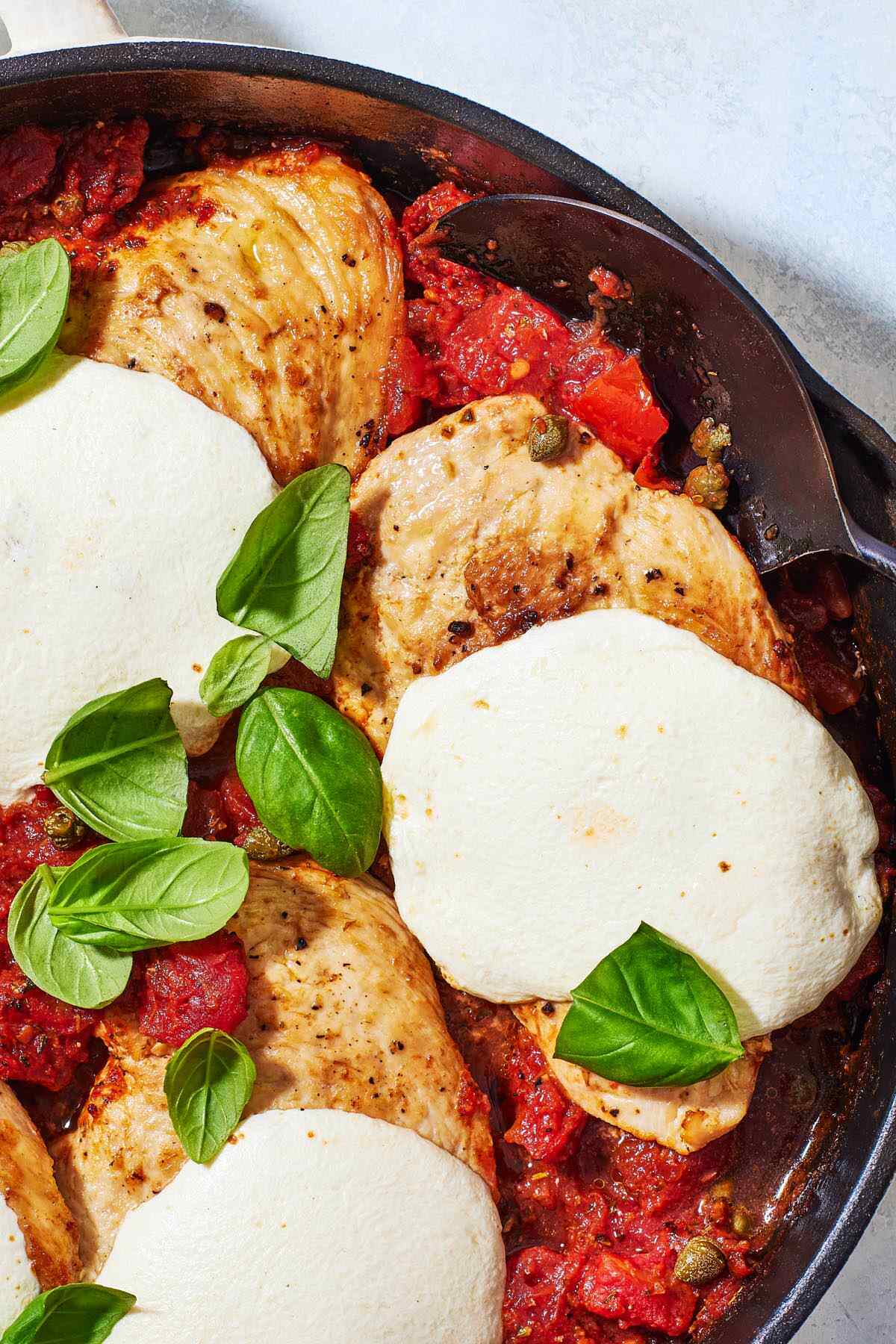 a close up of a skillet of pollo alla pizzaiola chicken in tomato sauce.