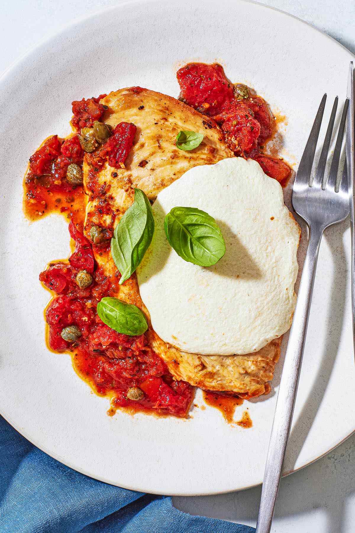 a serving of pollo alla pizzaiola chicken in tomato sauce on a plate with a fork.