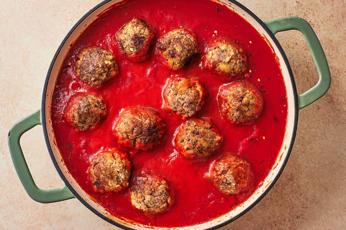 meatballs simmering in sauce in a large pot.