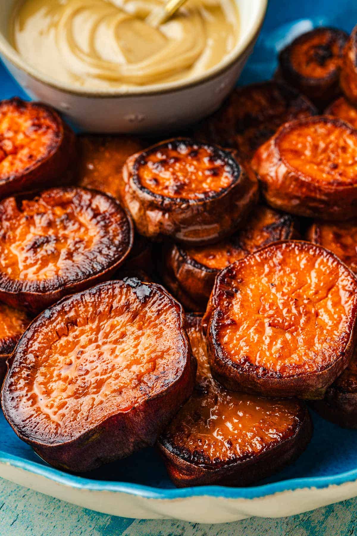 Close up shot of roasted sweet potato rounds stacked on a plate.