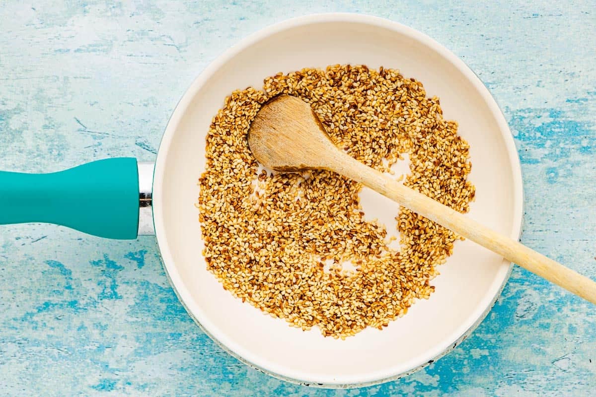 Toasted sesame seeds in a pan with a wooden spoon.