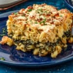 Piece of Spanakopita Mac and cheese, showing the layer of spinach, onion, and herb mixture in the center and the golden brown curst.