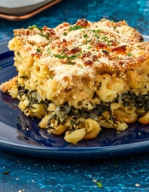 Corner piece that has been cut out of Spanakopita Mac and cheese, showing the layer of spinach, onion, and herb mixture in the center and the golden brown curst.