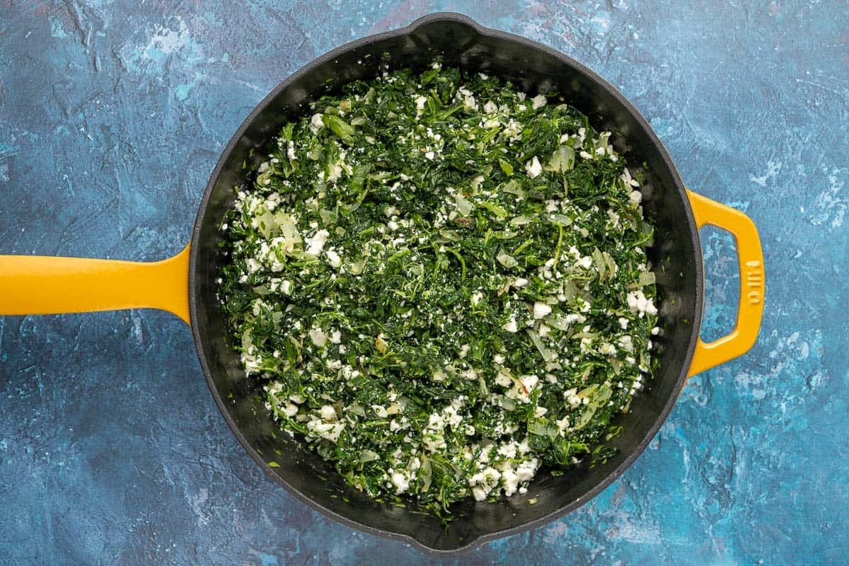 spinach, onion, garlic, parsley, thyme and feta cheese stirred together in a skillet.
