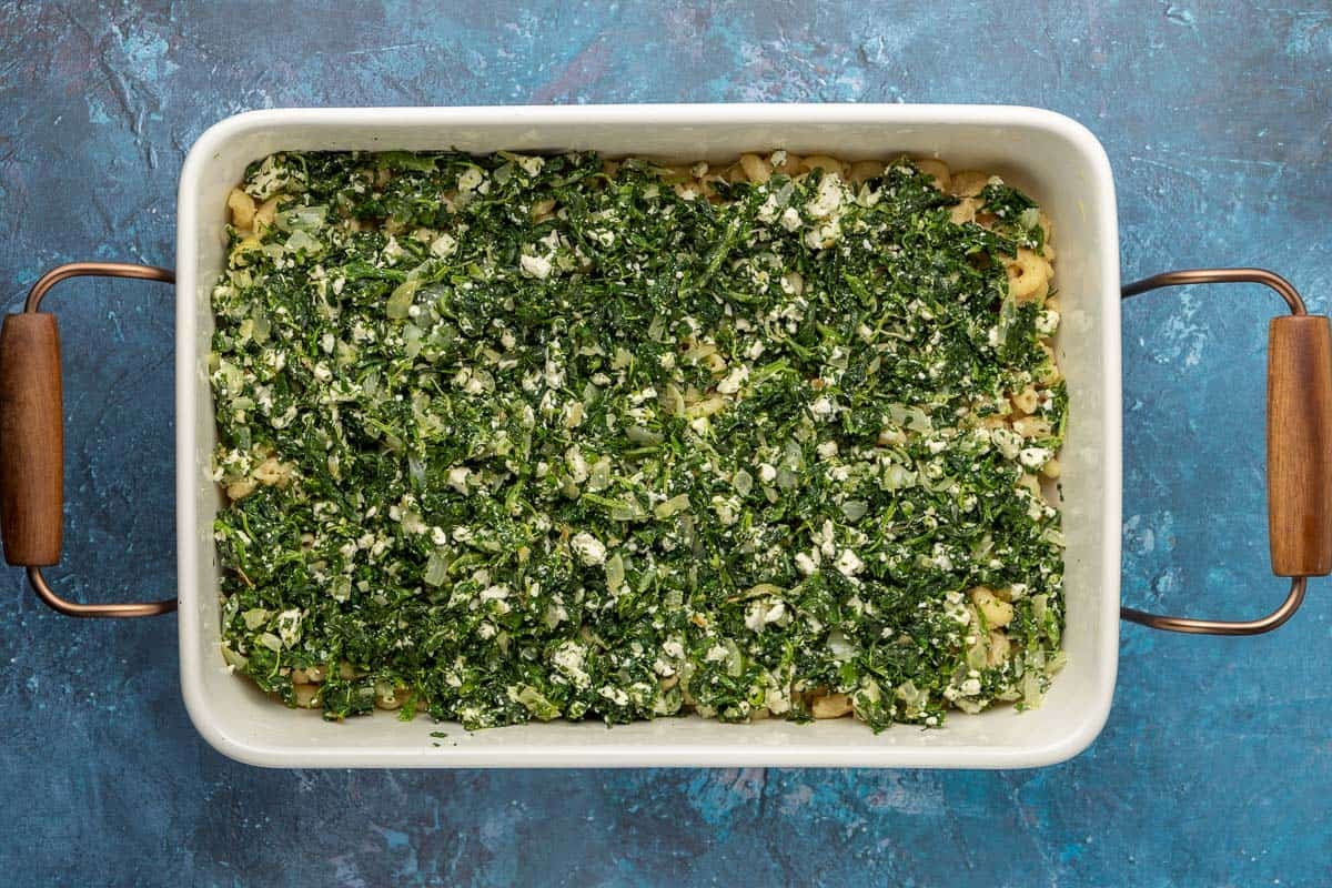 spinach, onion, garlic, parsley, thyme and feta cheese mixture spread on top of the elbow pasta in a large baking dish.