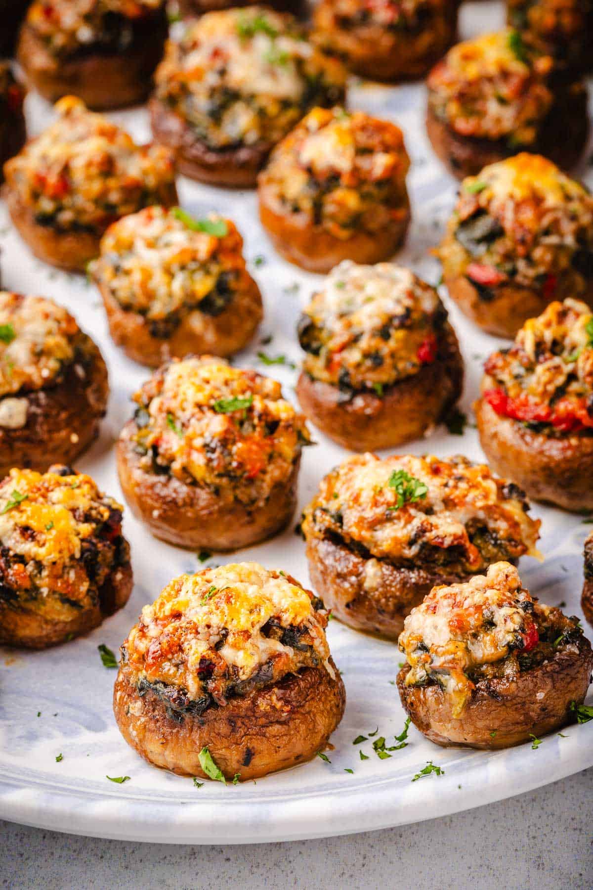 a close up of several baked stuffed mushrooms on a serving platter.