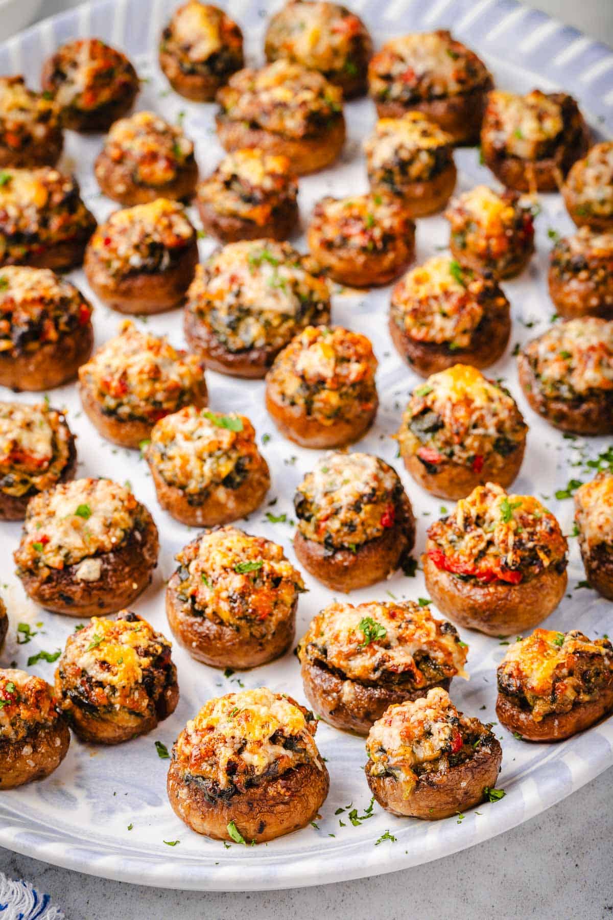 several baked stuffed mushrooms on a serving platter.