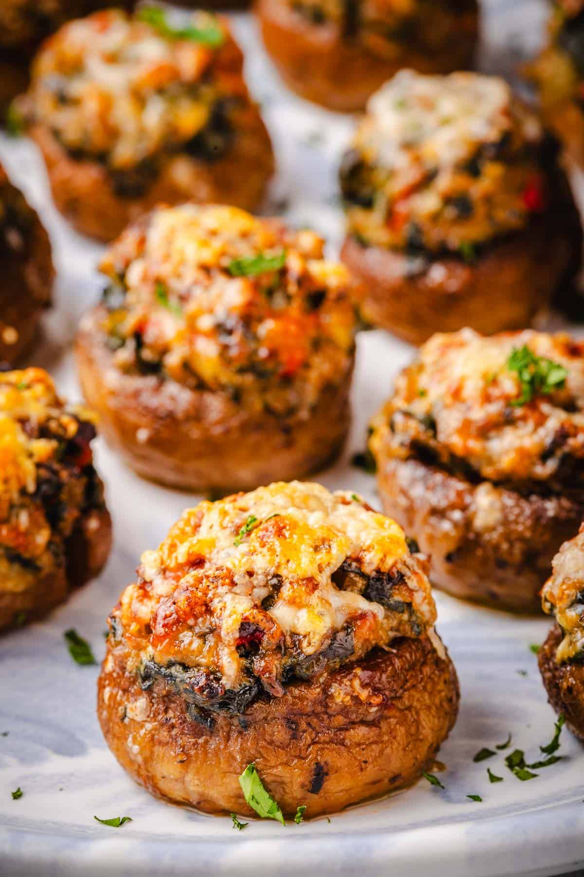 a close up of several baked stuffed mushrooms on a serving platter.