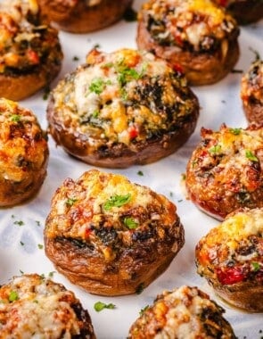 a close up of several baked stuffed mushrooms on a serving platter.