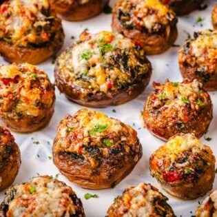 a close up of several baked stuffed mushrooms on a serving platter.