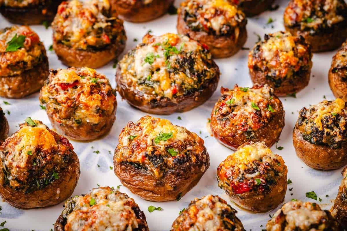 a close up of several baked stuffed mushrooms on a serving platter.