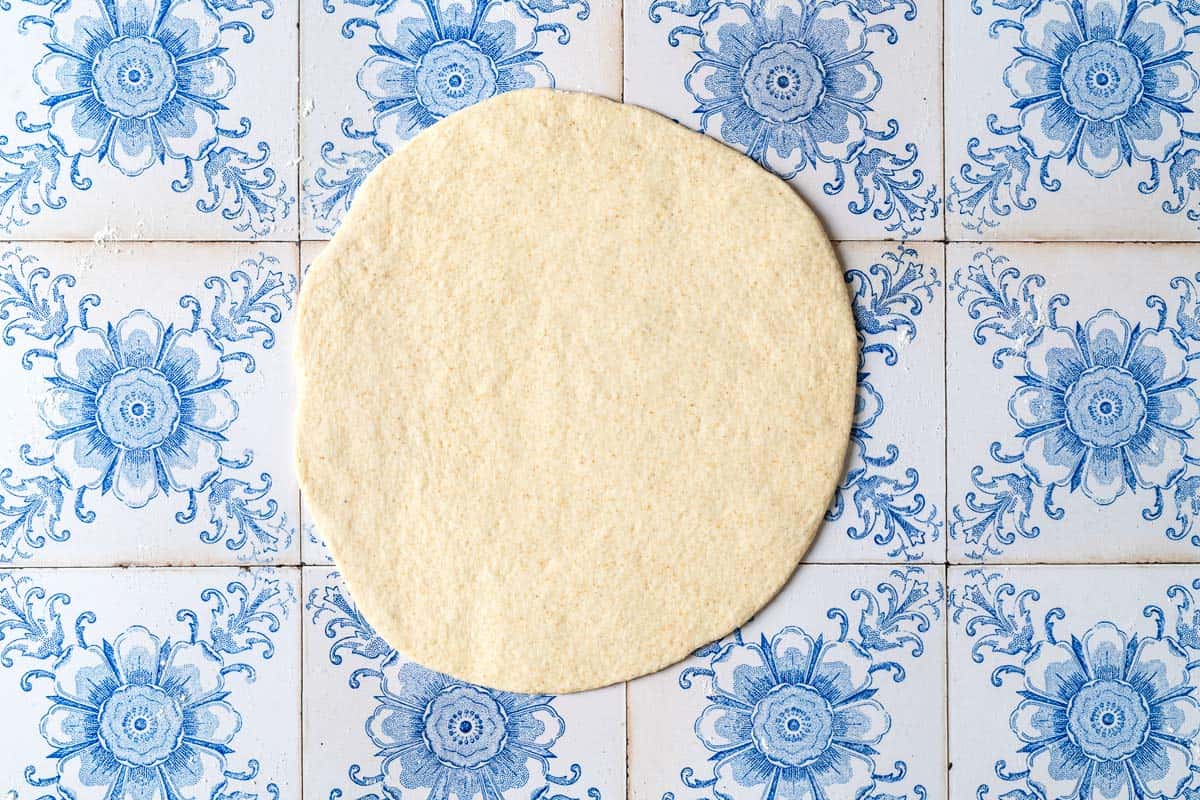 a piece of taboon flatbread dough rolled flat into a circle.