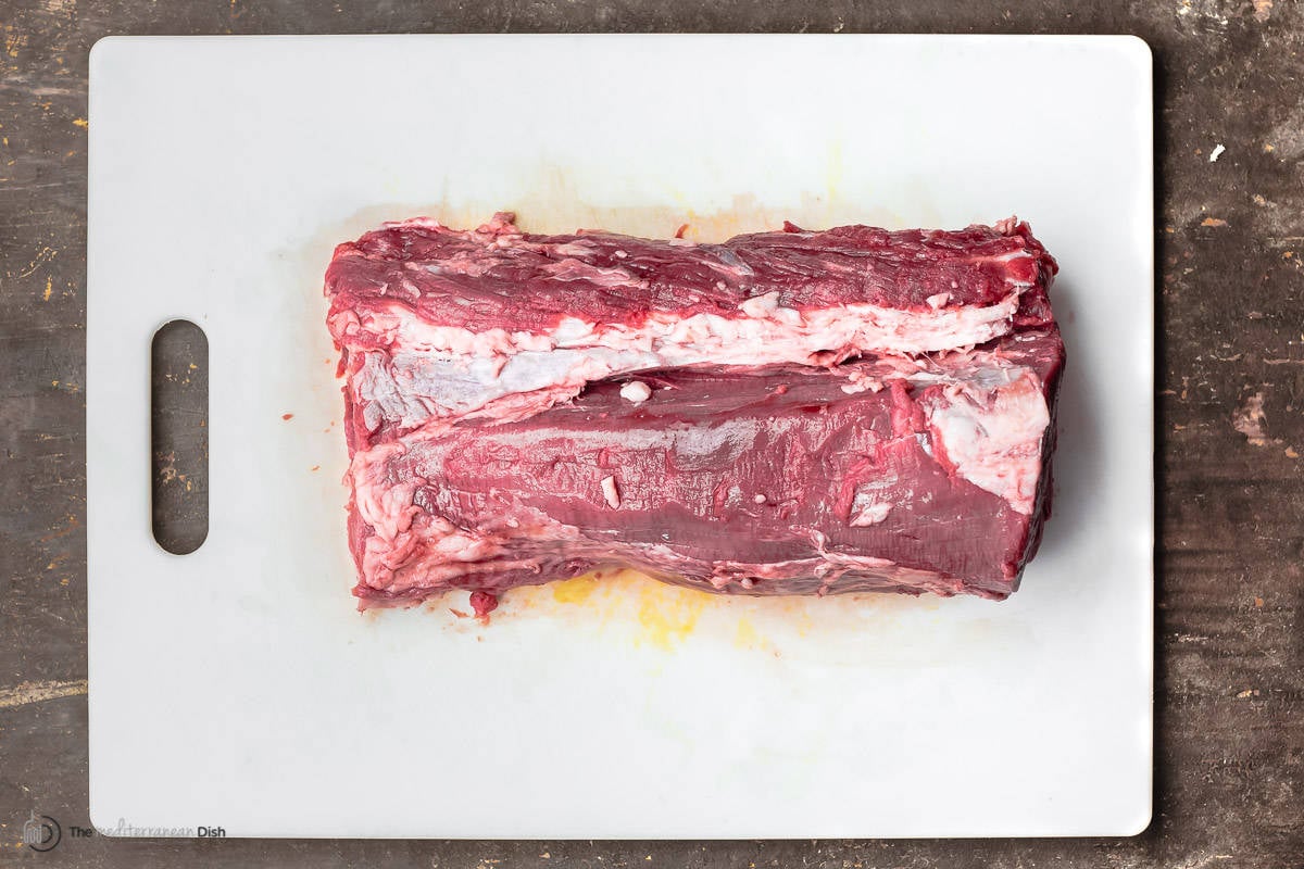 an uncooked beef tenderloin on a cutting board.