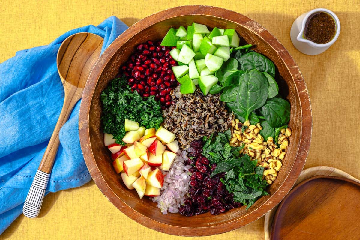 wild rice salad ingredients in a bowl in like groups, before it's tossed together and dressed.