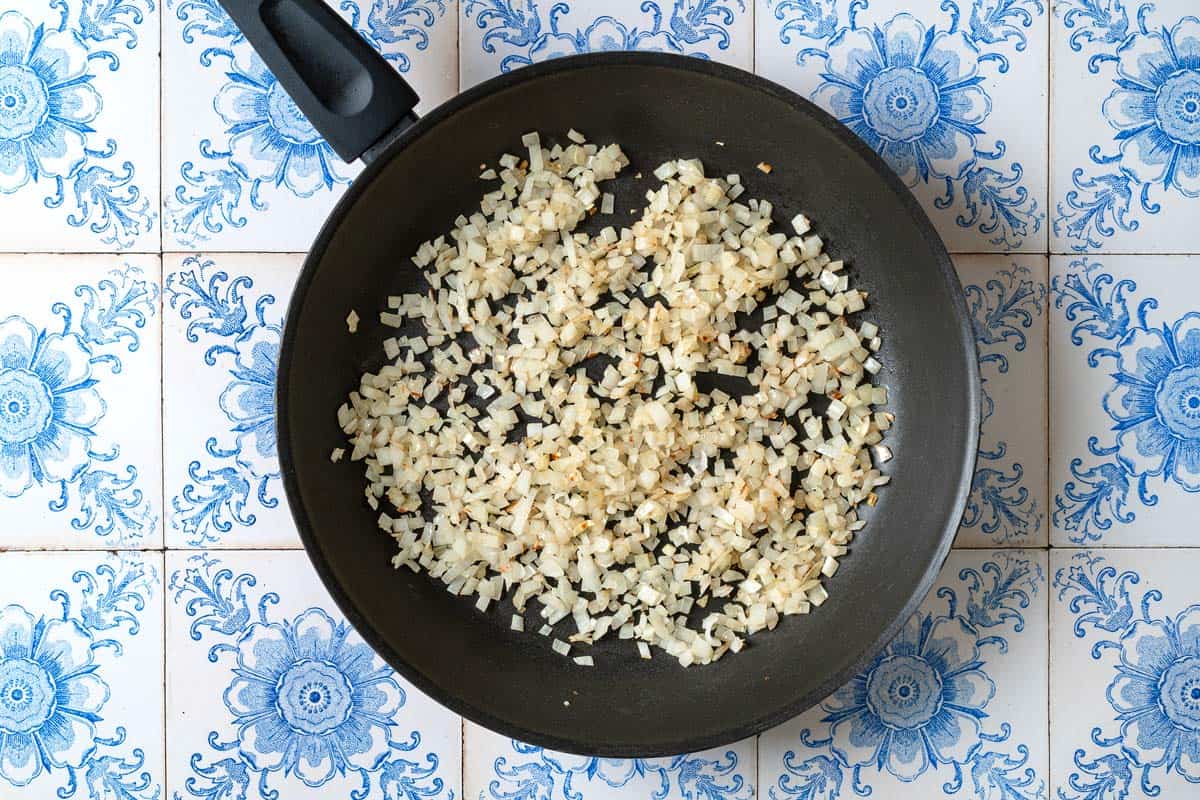 Chopped onions sautéing in a frying pan.