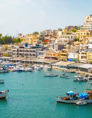 Image of boats in water in the Island of Crete with homes overlooking the water