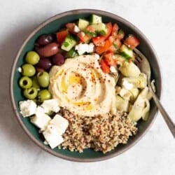 an overhead photo of a mediterranean bowl with quinoa with a fork in it.