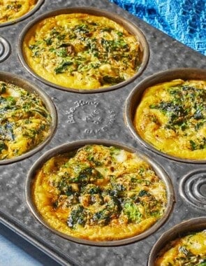 Spanakopita egg muffins in a muffin tin, showing the golden edges.