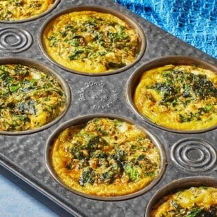 Spanakopita egg muffins in a muffin tin, showing the golden edges.