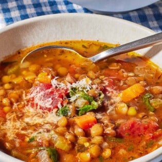 a close up of Italian lentil soup in a bowl with a spoon.