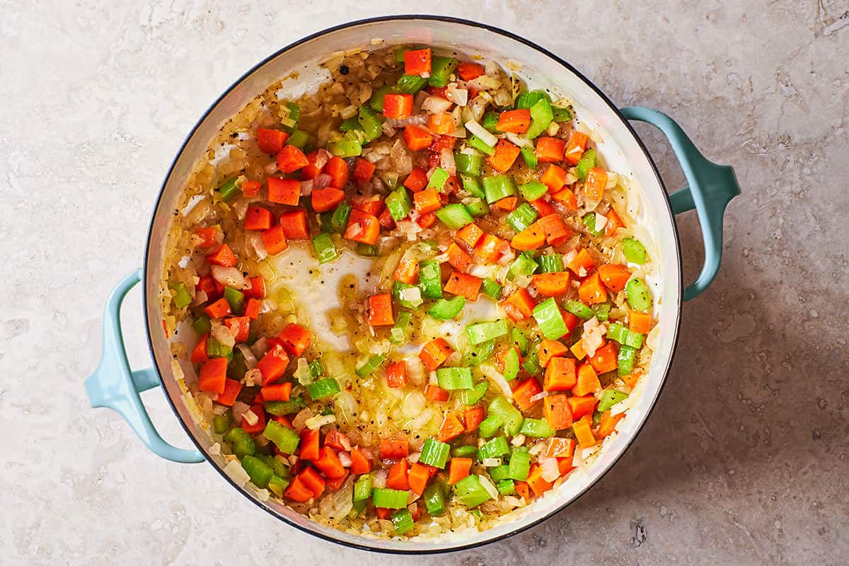 Saute the chopped onions, garlic, carrots, and celery in a large pot.