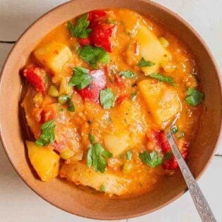 An overhead photo of a bowl of vegetable stew with a spoon.