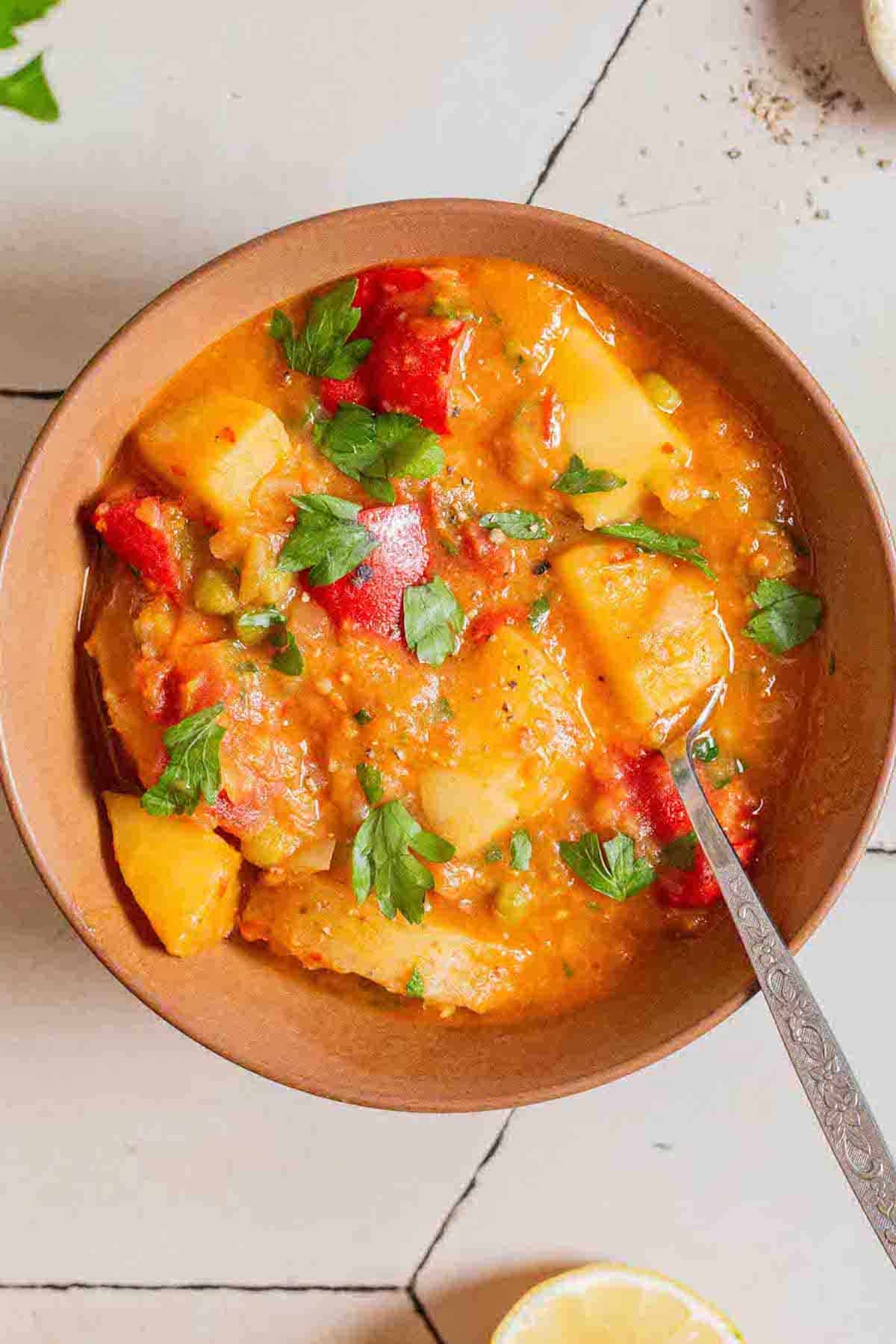 An overhead photo of a bowl of vegetable stew with a spoon.