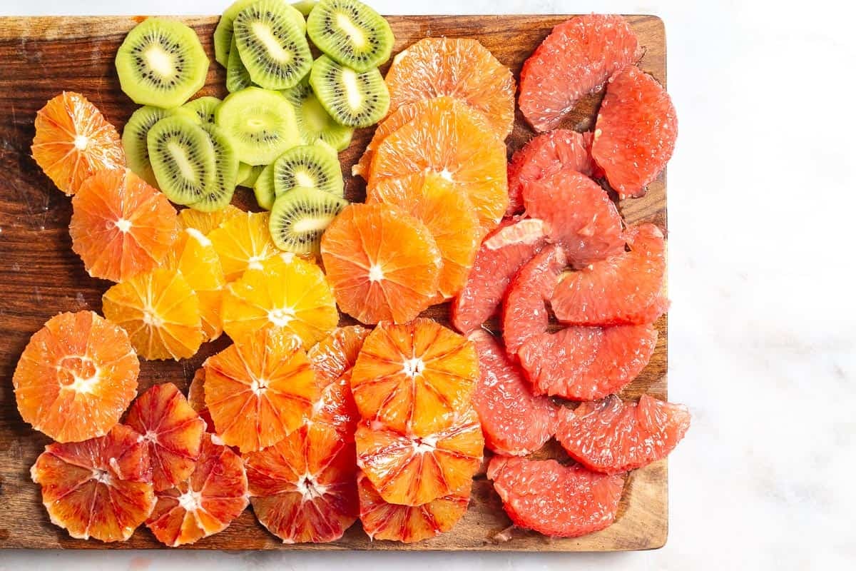 slices of kiwi, orange and grapefruit for the citrus salad on a cutting board.