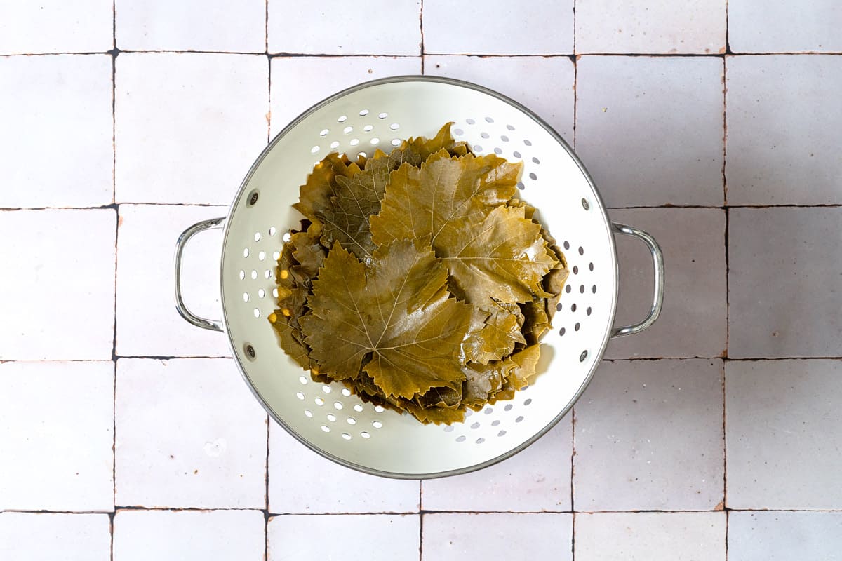 the grape leaves for the greek meatloaf sitting in a colander.