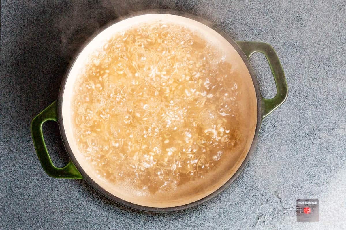 Brown rice boiling in water in a large pot.