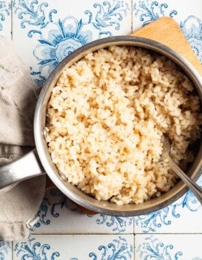 An overhead photo of brown in a saucepan with a spoon next to a cloth napkin.