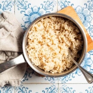 An overhead photo of brown in a saucepan with a spoon next to a cloth napkin.