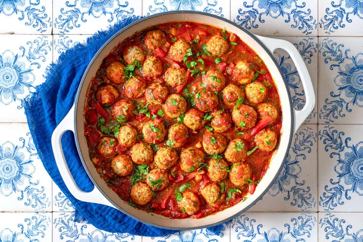 moroccan fish kofta in a large pot next to a blue cloth napkin.