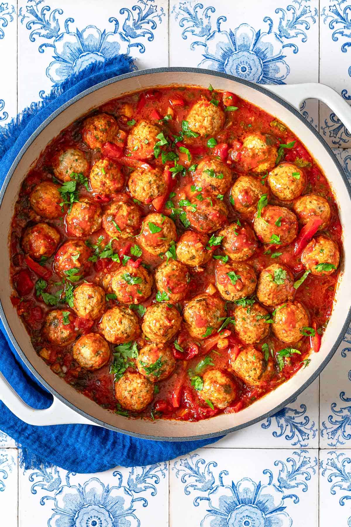 and overhead photo of moroccan fish kofta in a large pot next to a blue cloth napkin.