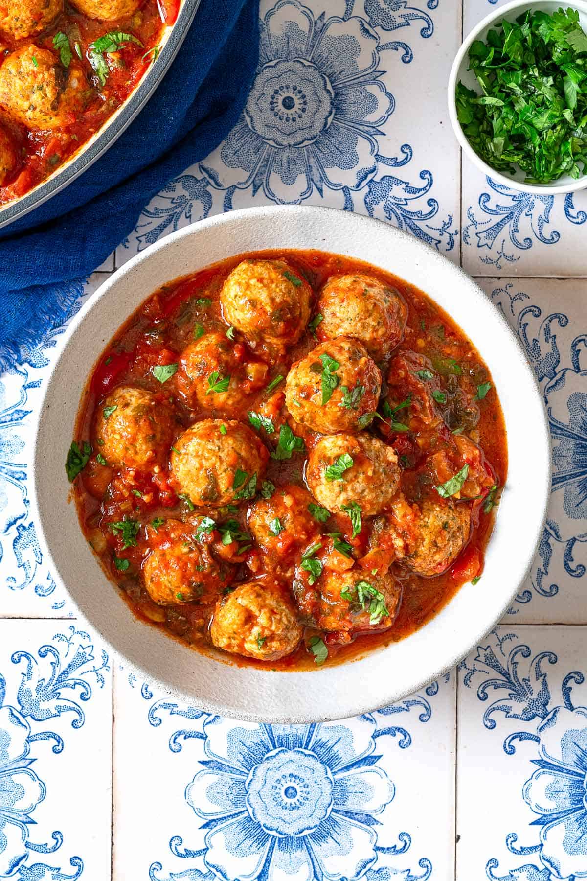 an overhead photo of a serving of moroccan fish kofta in a bowl next to a small bowl of parsley.