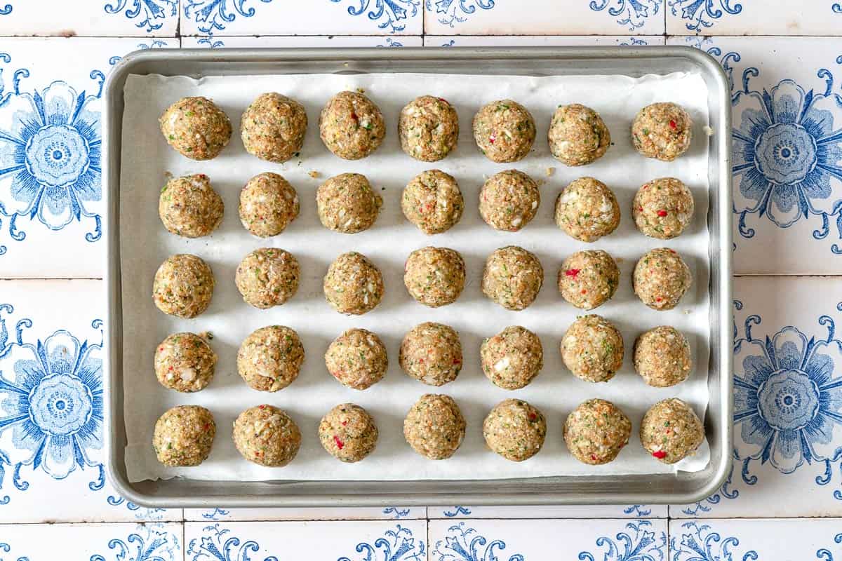 unbaked moroccan fish kofta spread evenly on a parchment lined baking sheet.