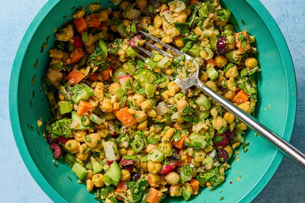 The vegan chickpea salad mixture in a mixing bowl with a fork.