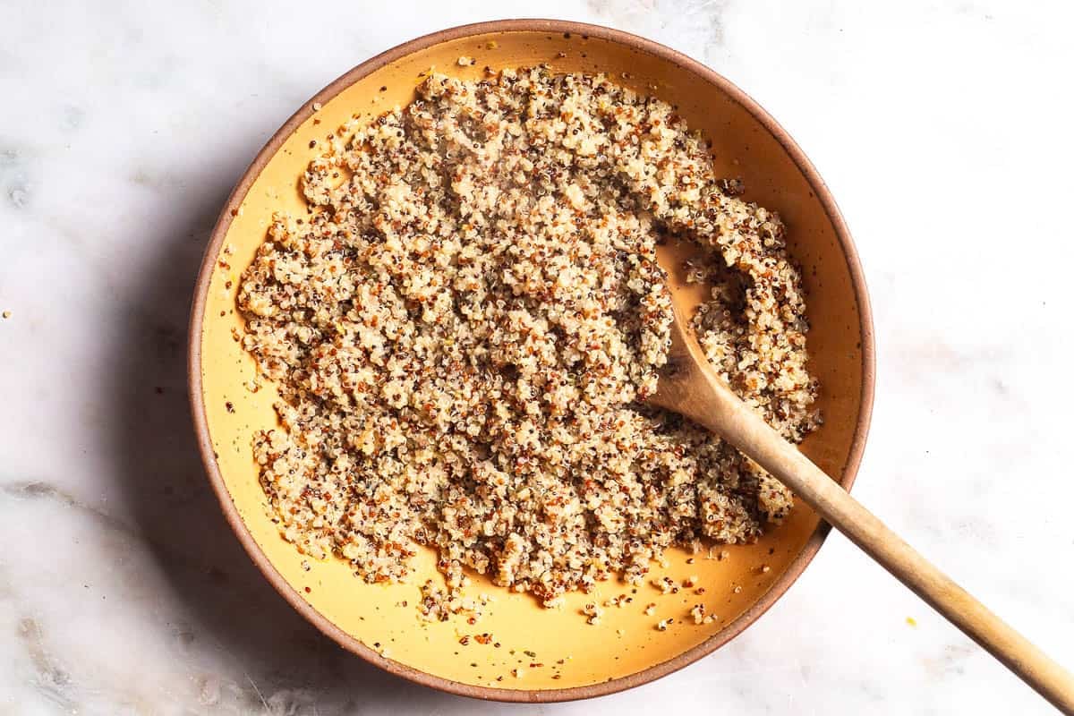 Cooked quinoa in a large bowl with a wooden spoon.