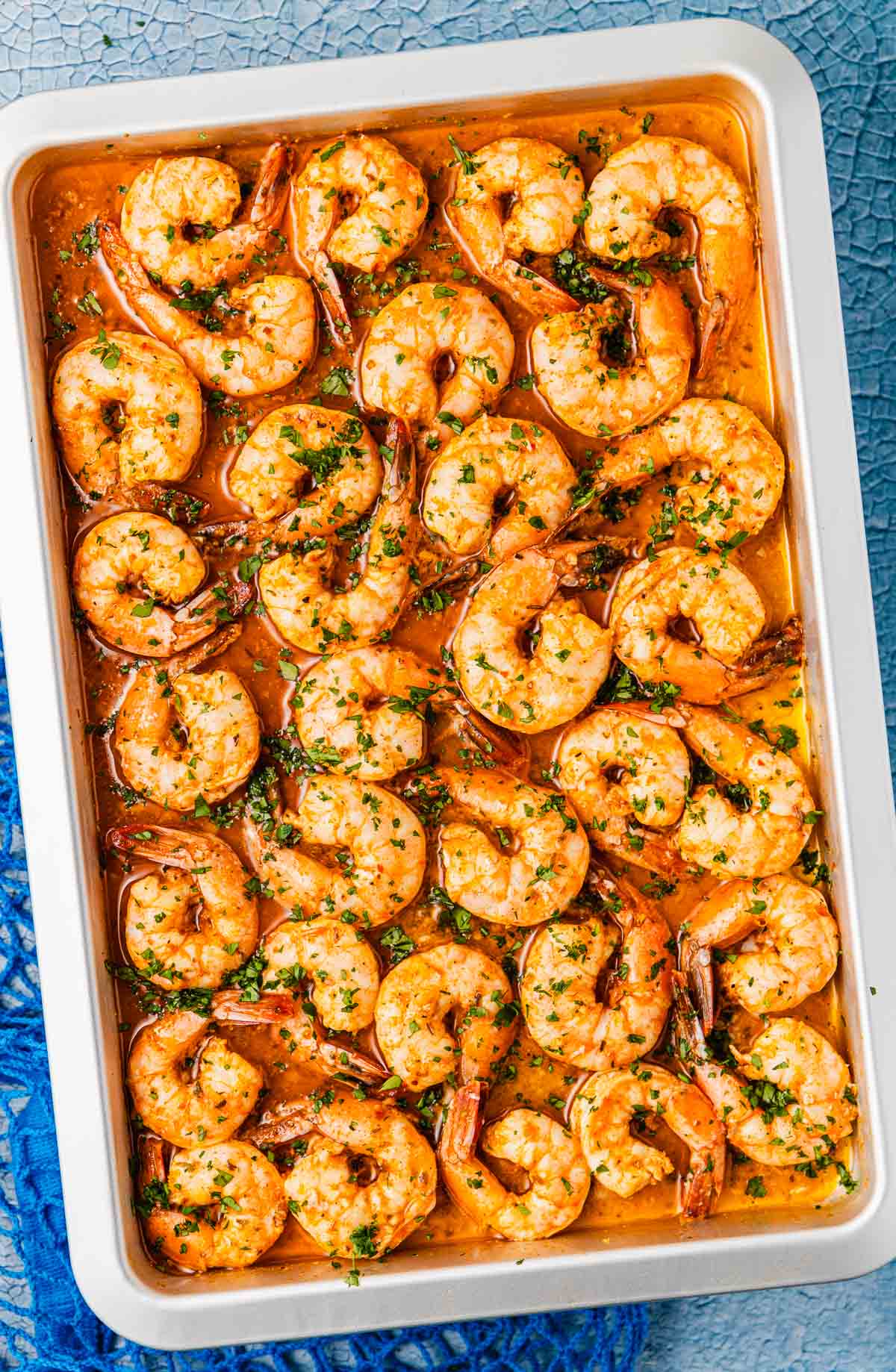 an overhead photo of sheet pan shrimp in sauce garnished with parsley.