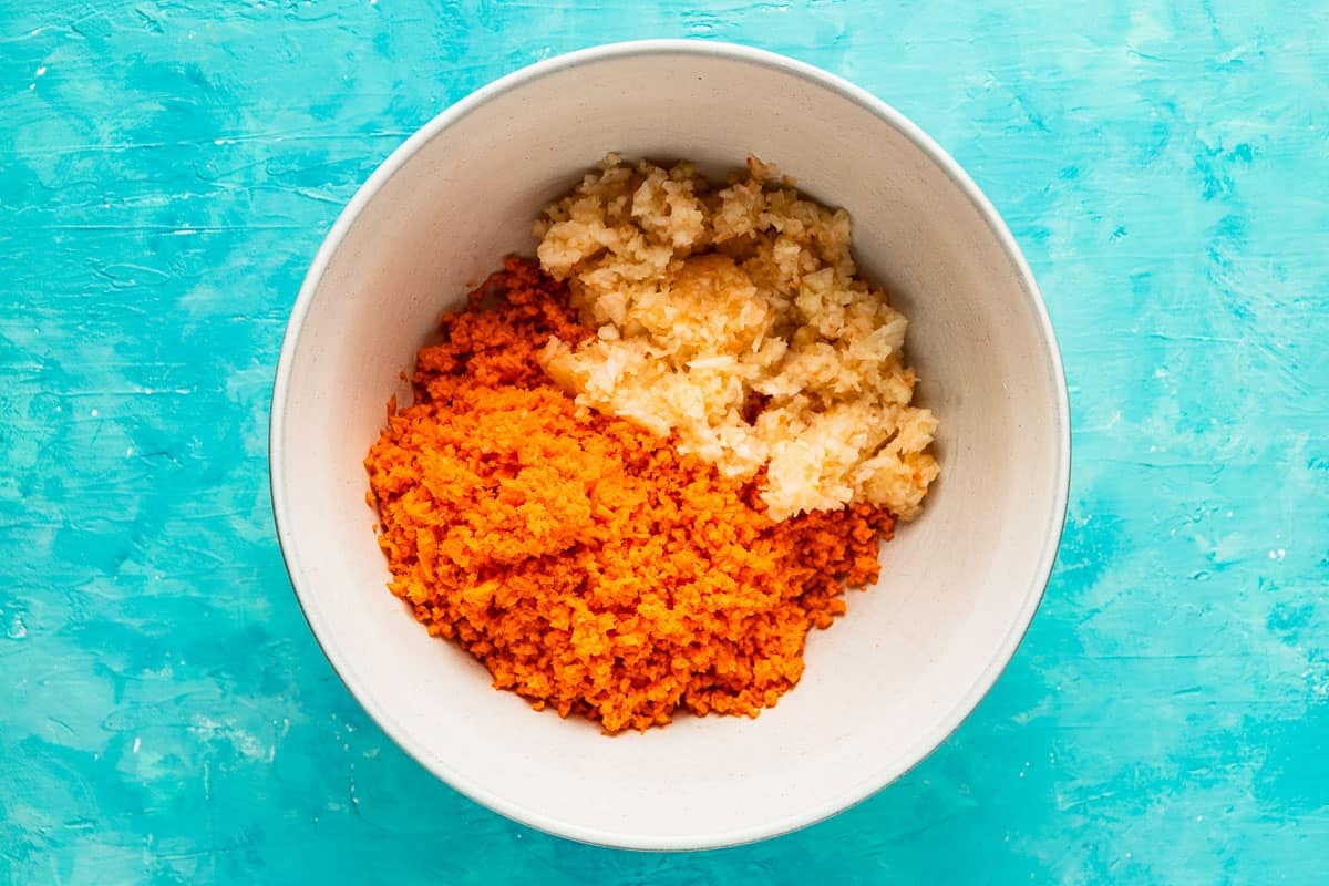 finely shredded carrots and onion in a white bowl.