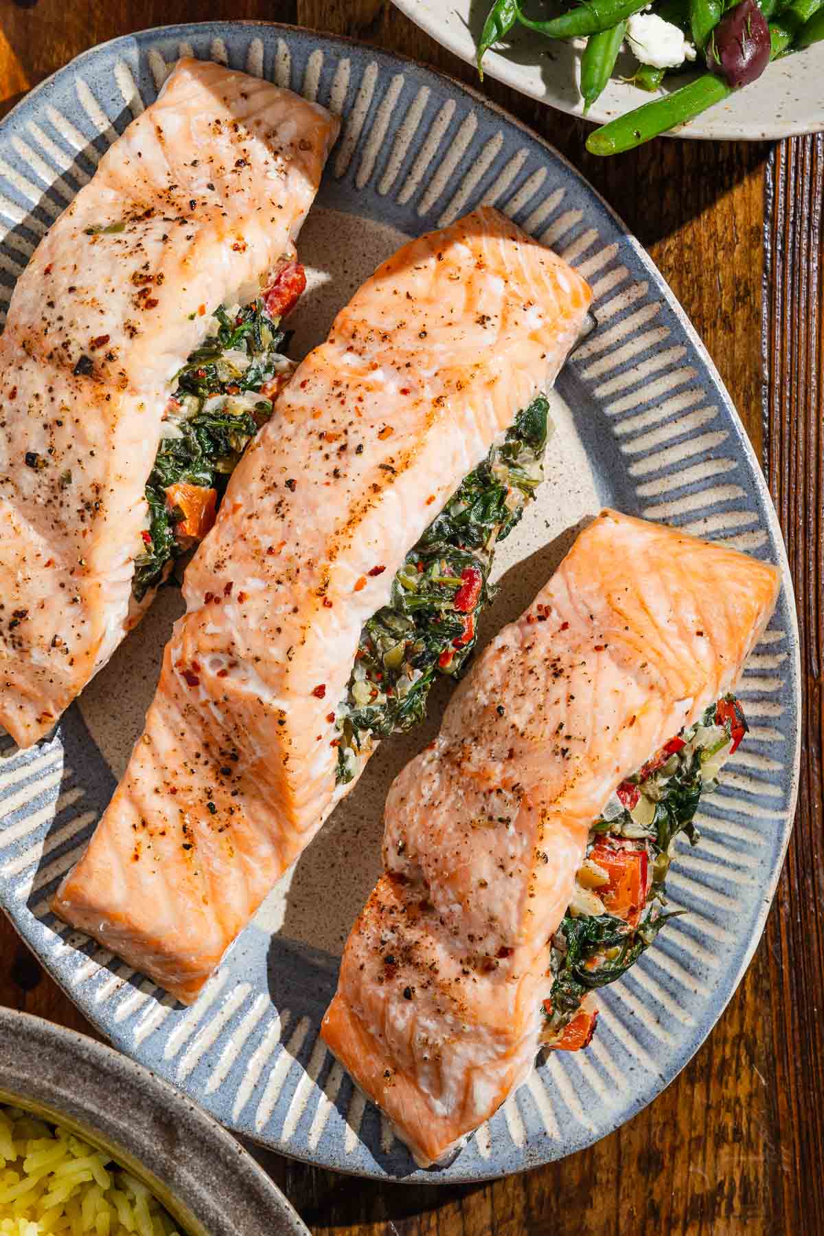 An overhead photo of three stuffed salmon fillets on a serving platter.