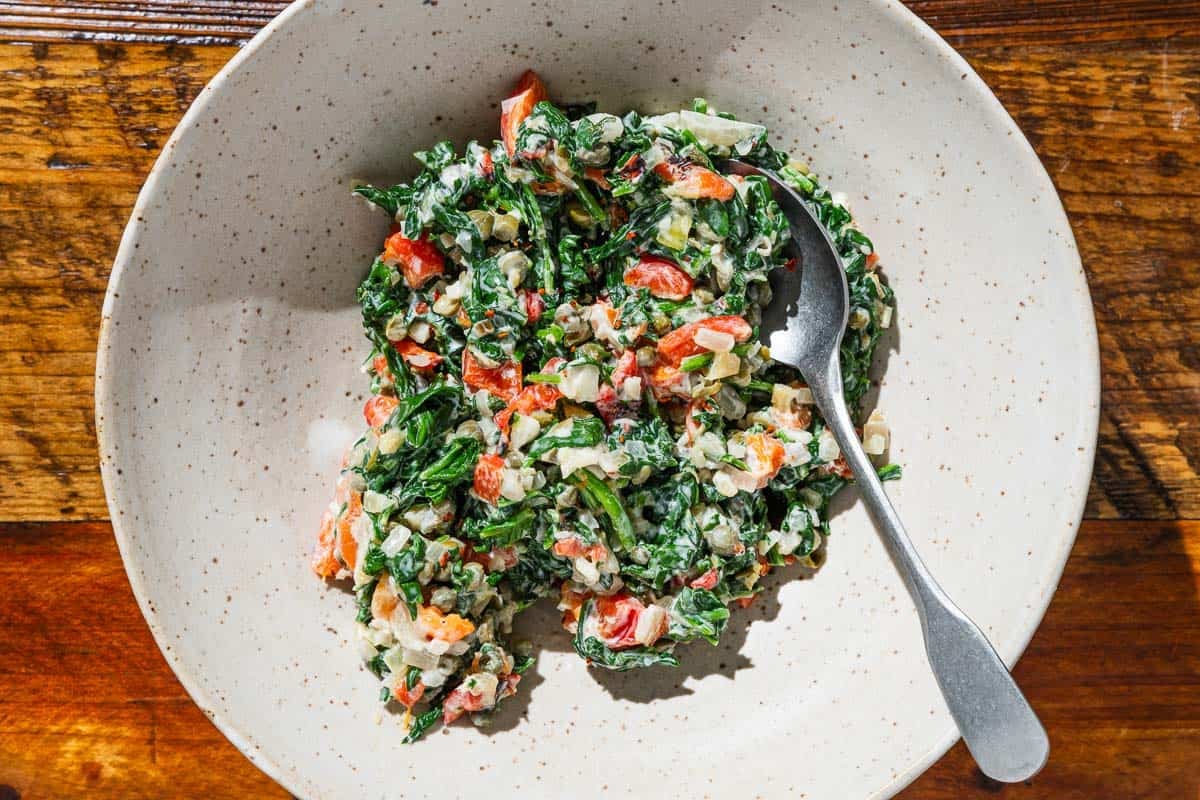 The spinach stuffing for the salmon in a bowl with a spoon.