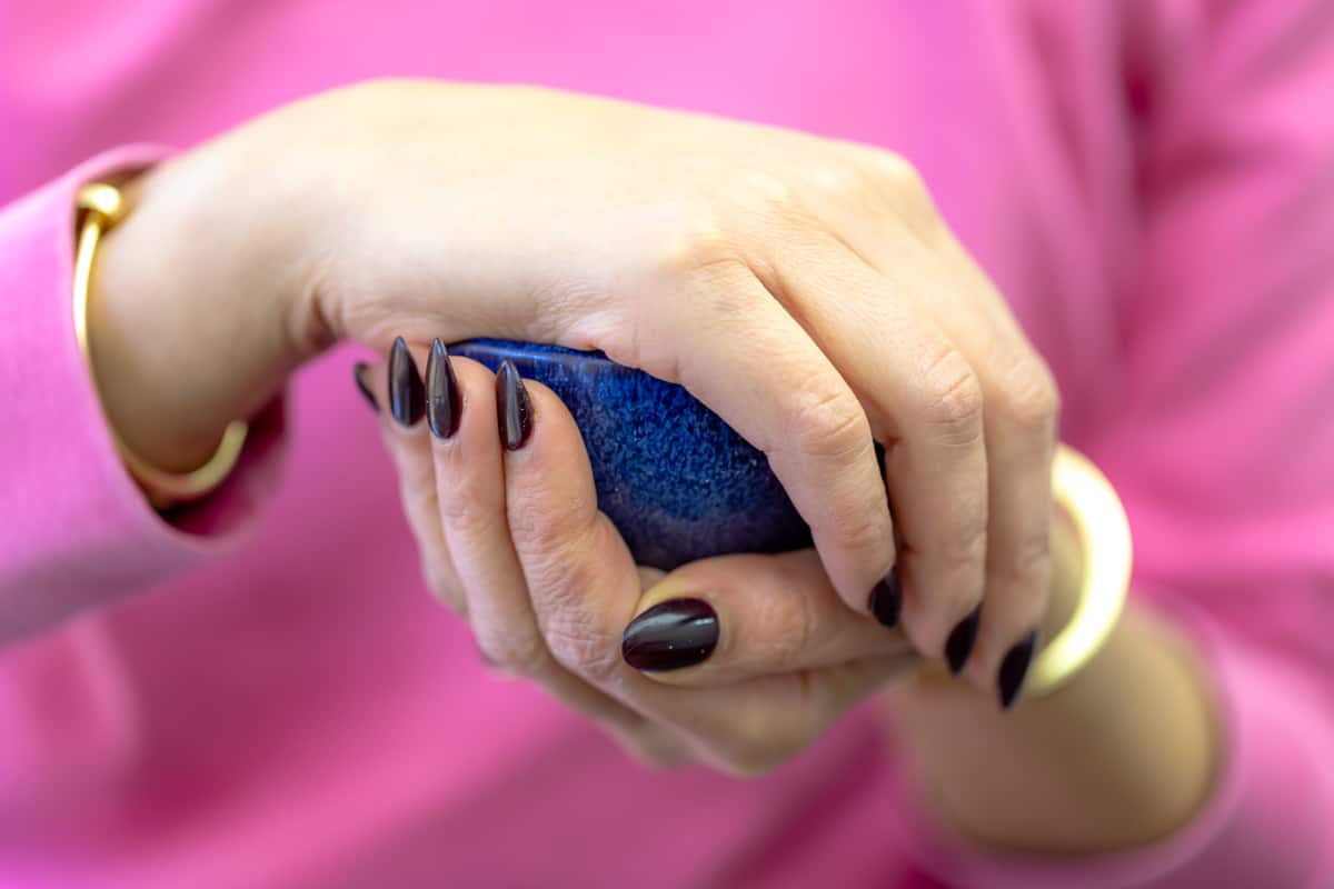 a picture of two hands cupping a small blue bowl containing olive oil.