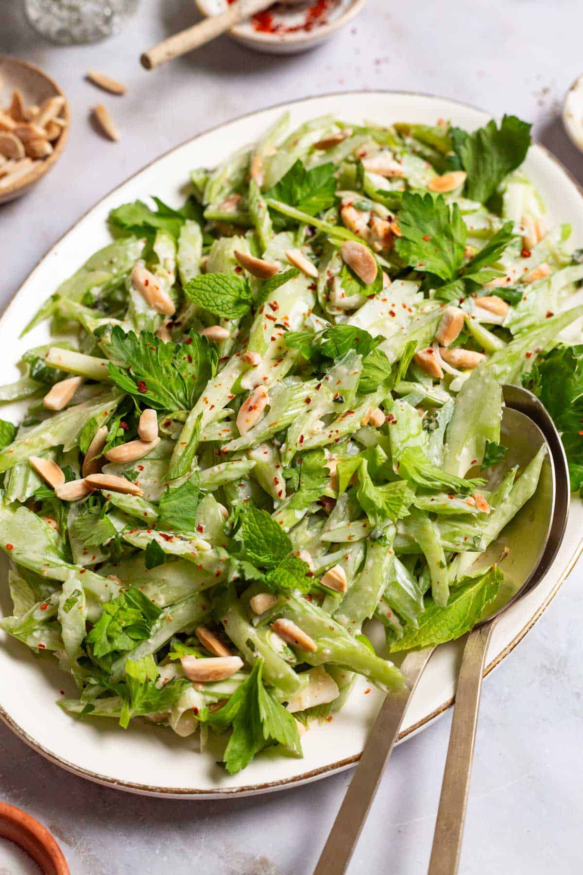 celery salad on a serving platter with serving utensils.