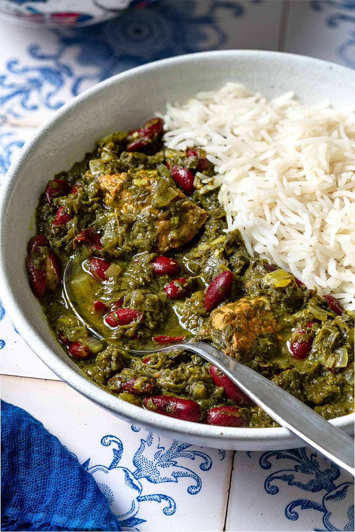 Ghormeh sabzi in a bowl with rice and a spoon.