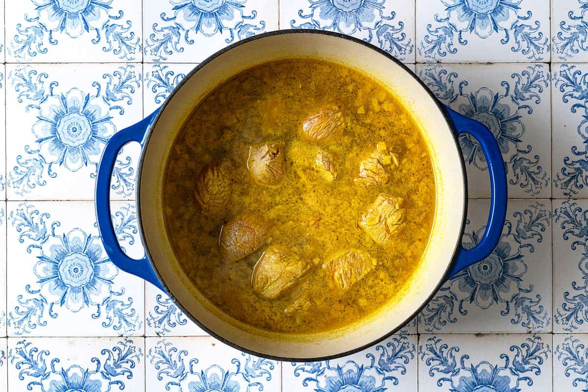 Beef for the ghormeh sabzi cooking in a large pot of turmeric and water.